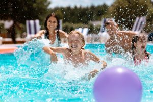Ball,In,Pool.,Cheerful,Happy,Parents,And,Children,Laughing,While